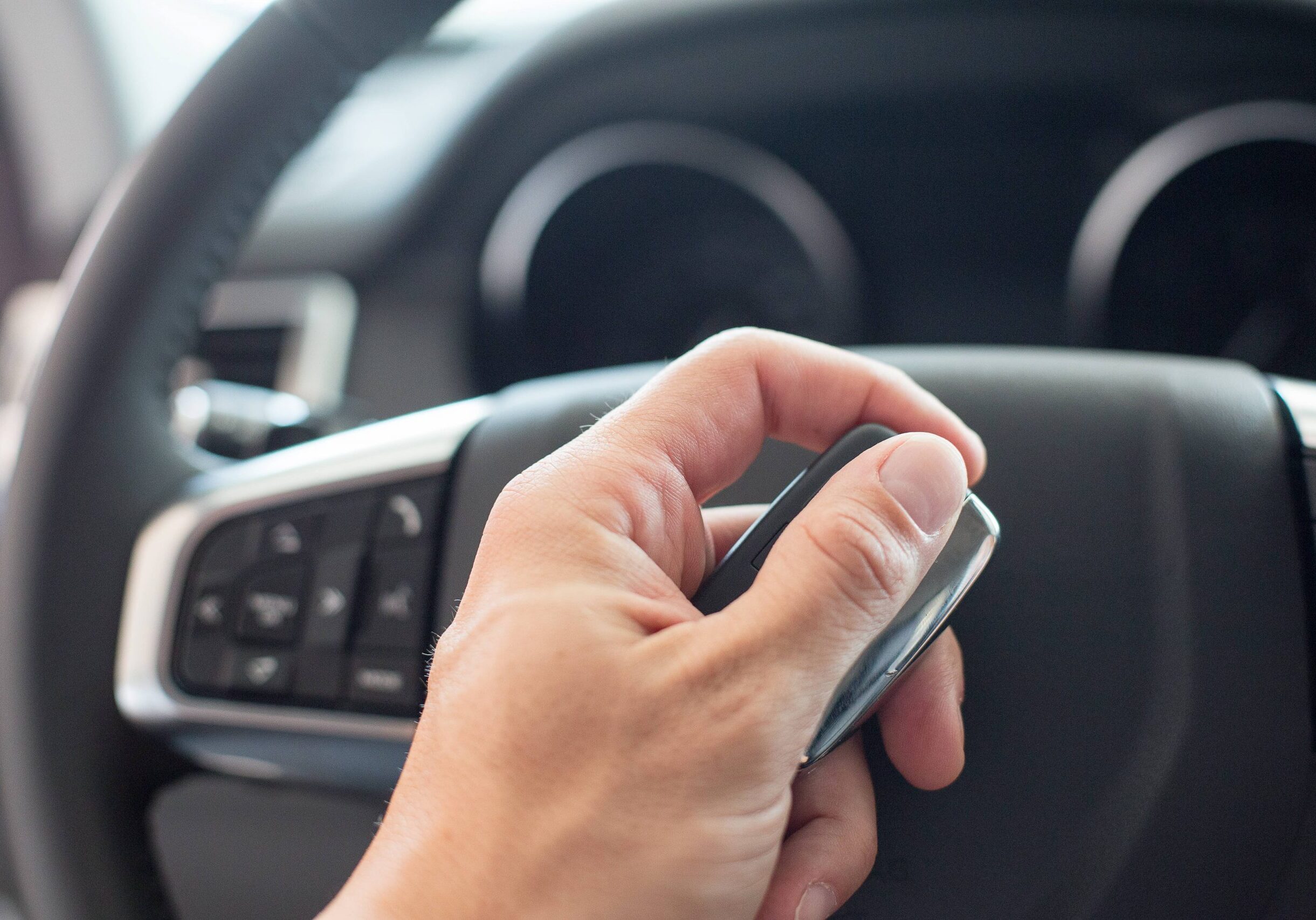 male-hand-holding-a-car-key-and-steering-wheel-6LFSVYE-scaled Car Key Replacement Rushden